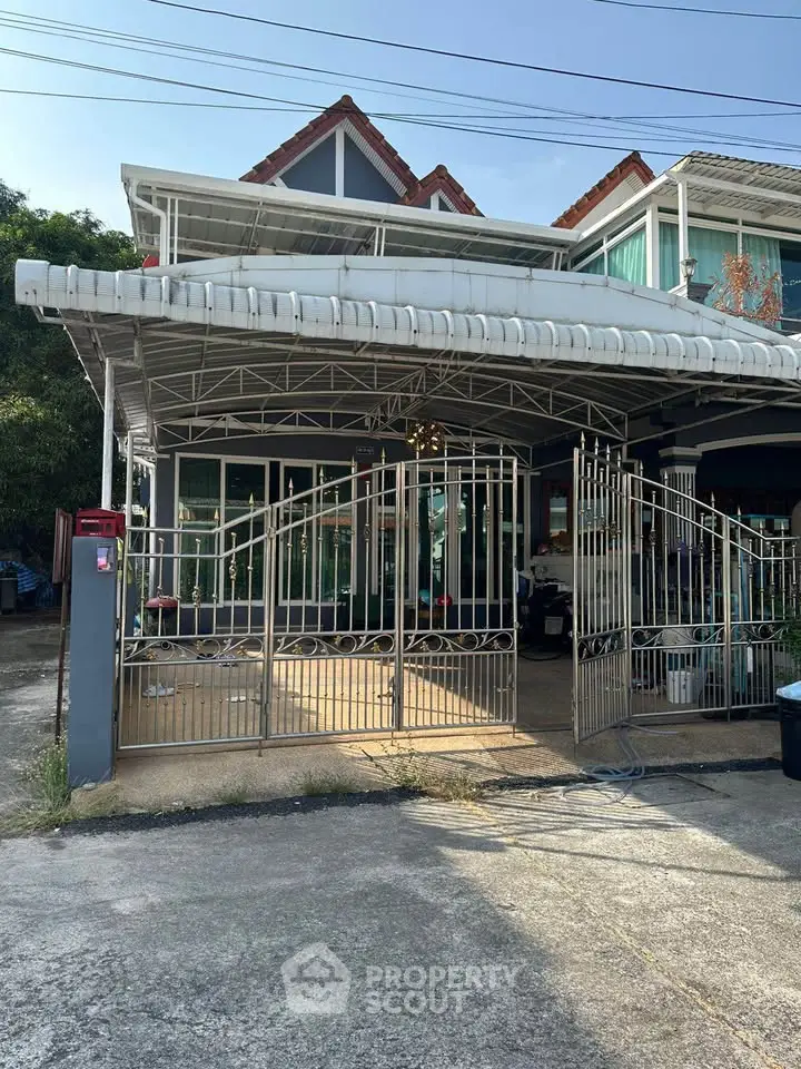 Charming two-story house with gated entrance and covered carport in a serene neighborhood.