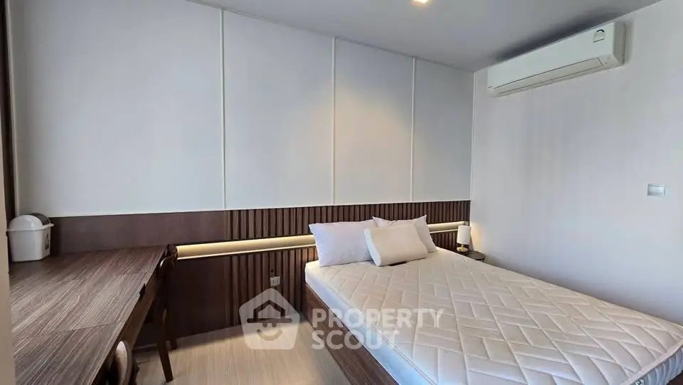 Modern bedroom with sleek design and air conditioning, featuring a comfortable bed and stylish wooden furniture.