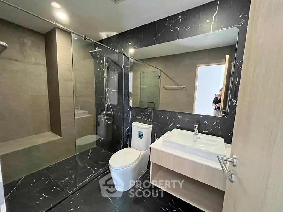 Modern bathroom with sleek black marble tiles and glass shower enclosure