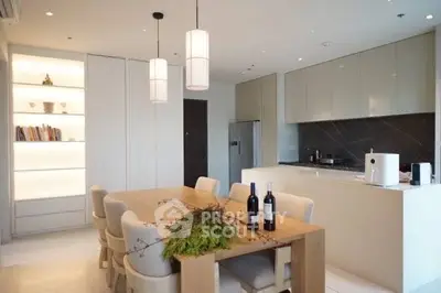 Modern kitchen with sleek cabinets and dining area, featuring elegant lighting and stylish decor.