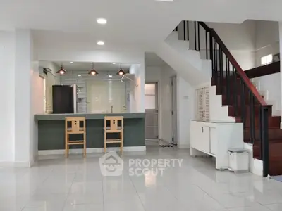 Spacious modern living area with stylish staircase and open kitchen layout.
