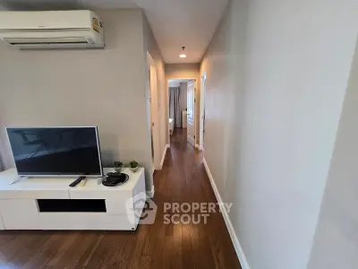 Modern apartment hallway with wooden flooring and sleek TV setup