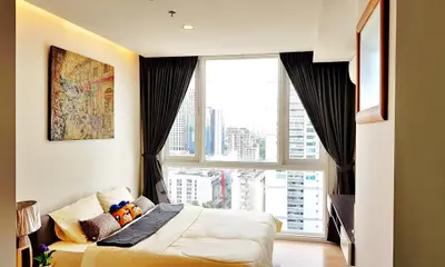 Modern bedroom with large window offering stunning city view, elegant decor, and cozy ambiance.