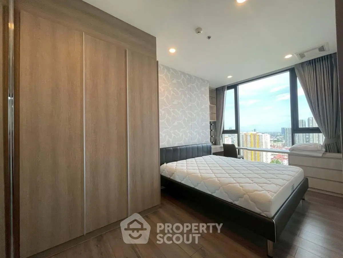 Modern bedroom with large window offering stunning city view, featuring sleek furniture and elegant decor.