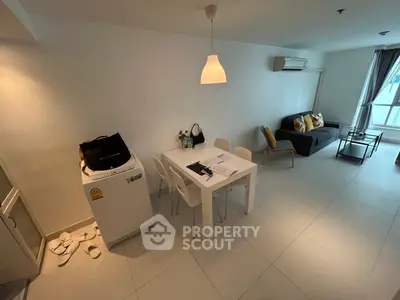 Modern living room with dining area and washing machine, featuring sleek furniture and bright lighting.