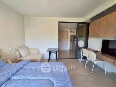 Modern studio apartment with cozy bed, compact kitchen, and workspace in open layout.
