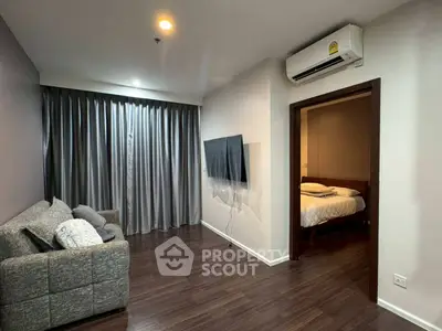 Modern living room with cozy sofa and wall-mounted TV, leading to a bedroom with elegant decor.
