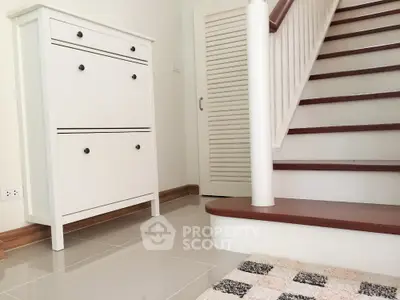 Stylish interior with modern staircase and sleek storage unit in a contemporary home.
