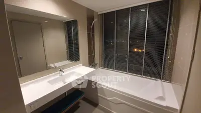 Modern bathroom with sleek bathtub and large mirror, featuring elegant tile design and ambient lighting.