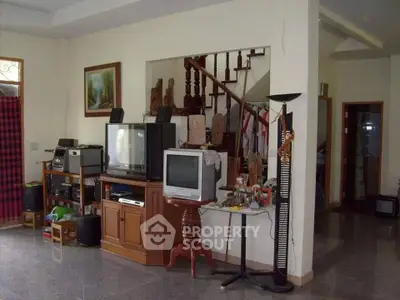 Spacious living room with vintage TV setup and elegant staircase