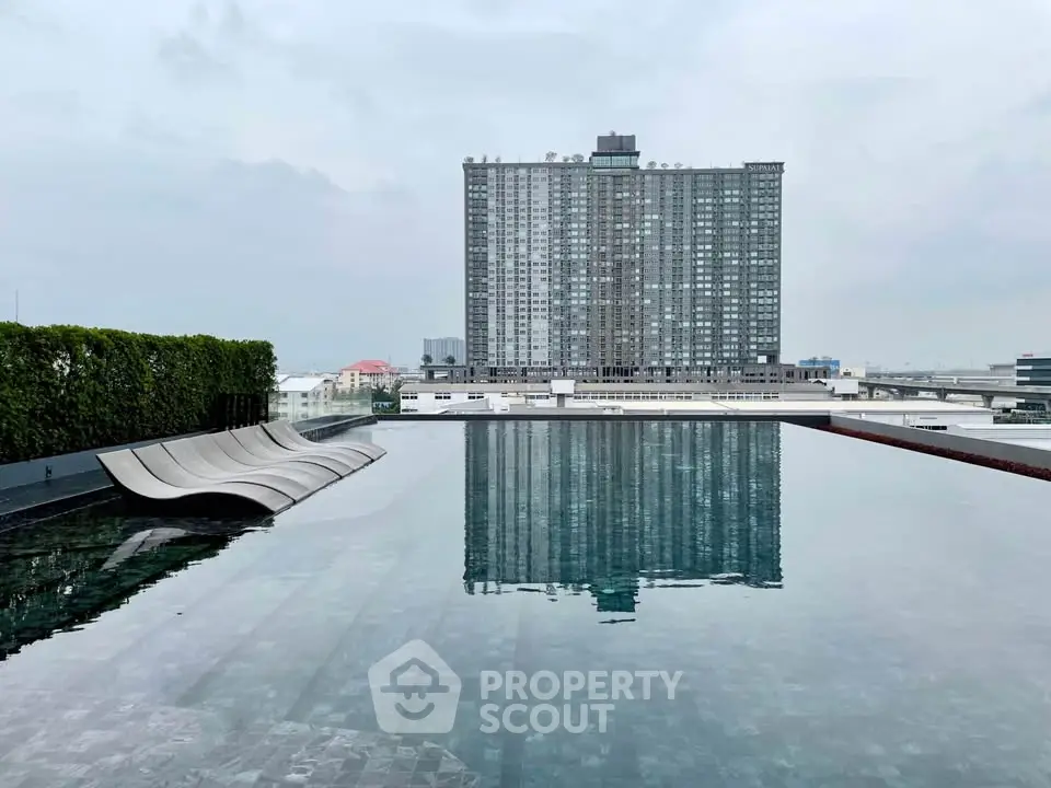 Luxurious rooftop pool with stunning cityscape view and modern high-rise building backdrop.