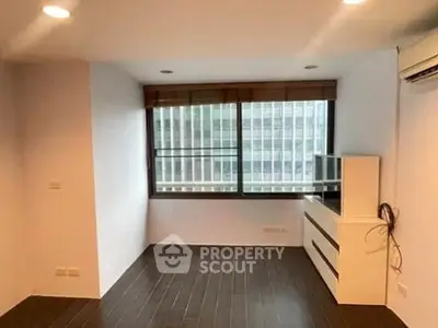 Spacious living room with large window and modern air conditioning unit