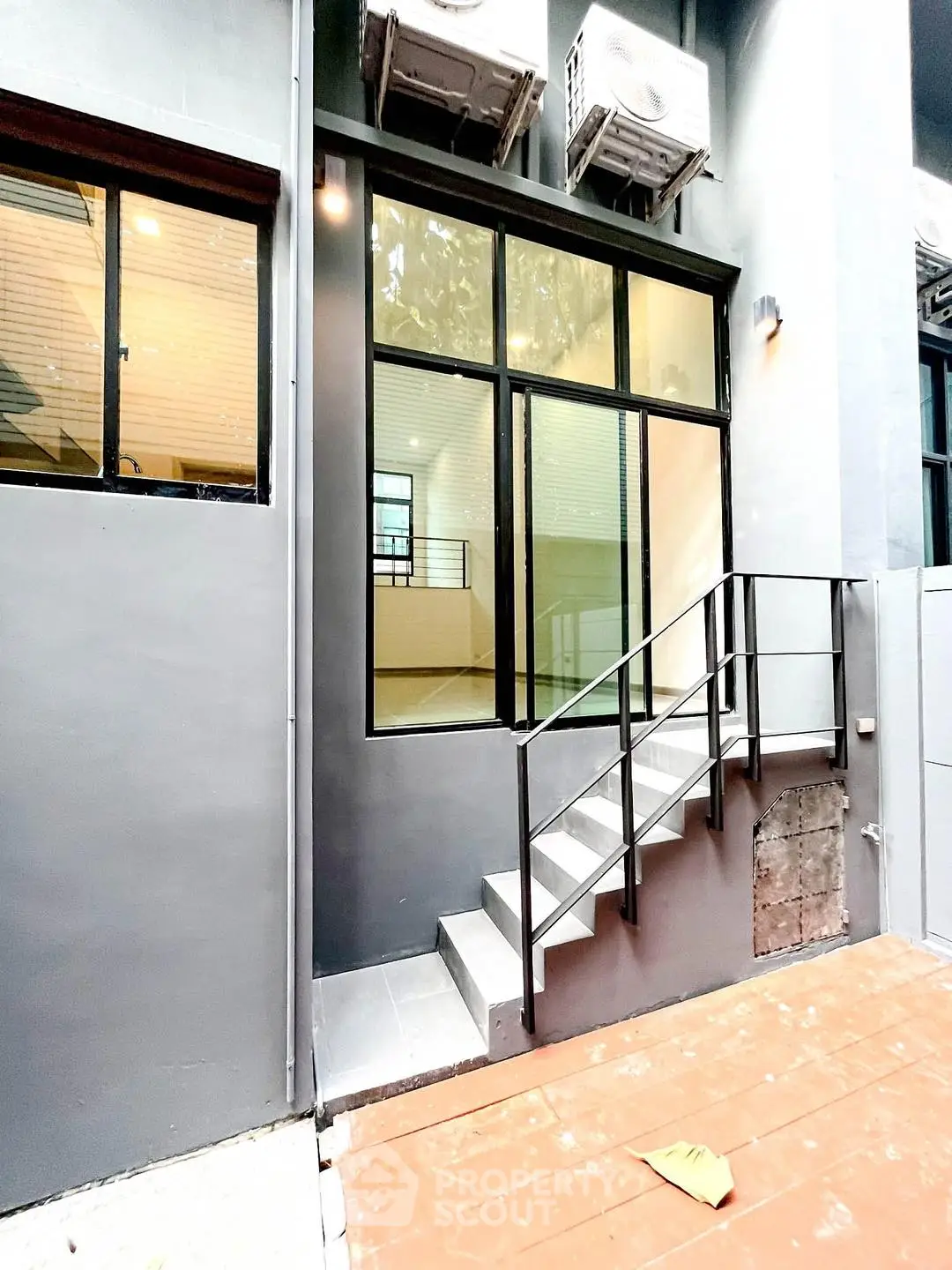 Modern industrial-style exterior with sleek metal staircase and large windows.