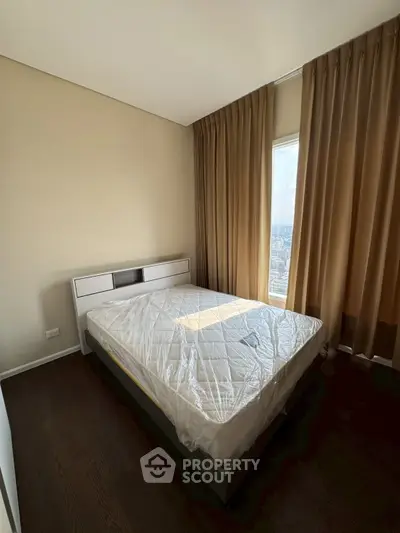 Modern bedroom with large window and elegant curtains, featuring a comfortable bed and wooden flooring.