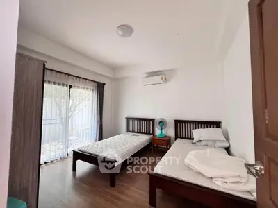 Bright bedroom with twin beds, air conditioning, and large window for natural light.