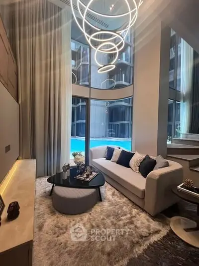 Luxurious living room with modern decor and pool view, featuring elegant lighting and plush furnishings.