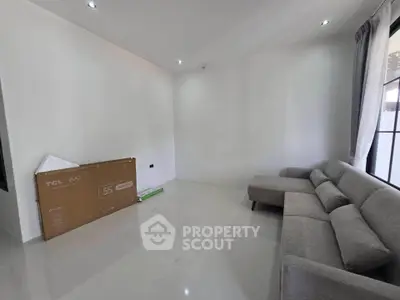 Spacious living room with modern gray sofa and large window, perfect for relaxation and entertainment.