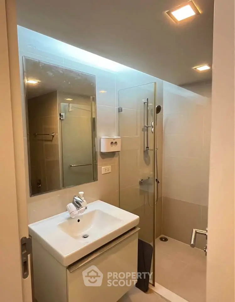 Modern bathroom with glass shower and sleek vanity in contemporary apartment.
