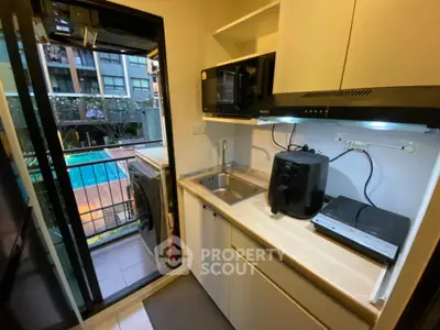 Compact kitchen with modern appliances and pool view from balcony