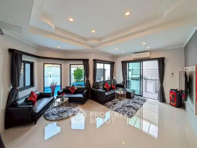 Spacious modern living room with sleek black sofas, elegant decor, and large windows offering natural light.