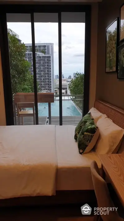 Modern bedroom with balcony and city view, featuring stylish decor and natural light.