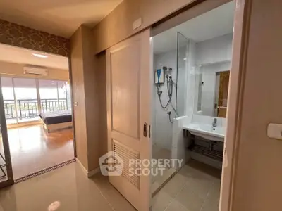 Modern apartment interior with bathroom and bedroom, featuring sliding door and balcony view.