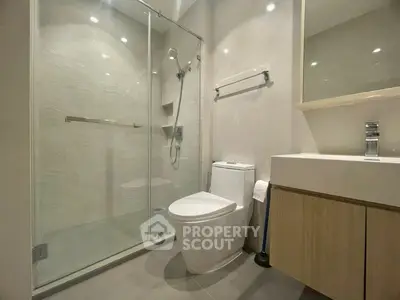 Modern bathroom with glass shower and sleek fixtures in contemporary apartment.