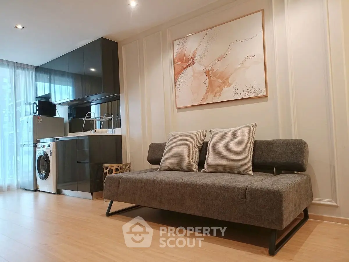 Modern living room with sleek kitchen and stylish sofa in open layout apartment.