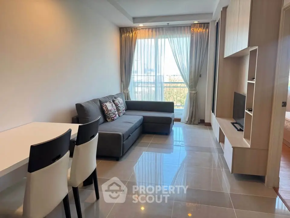 Modern living room with sleek furniture and large window offering natural light.