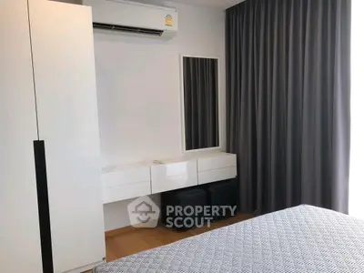 Modern bedroom with sleek furniture and air conditioning, featuring a stylish curtain and mirror.