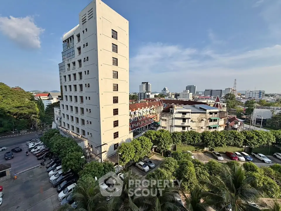 Stunning cityscape view from high-rise building with lush greenery and ample parking space.