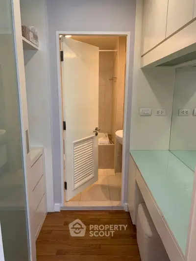 Compact bathroom with modern fixtures and wooden flooring in a cozy apartment.
