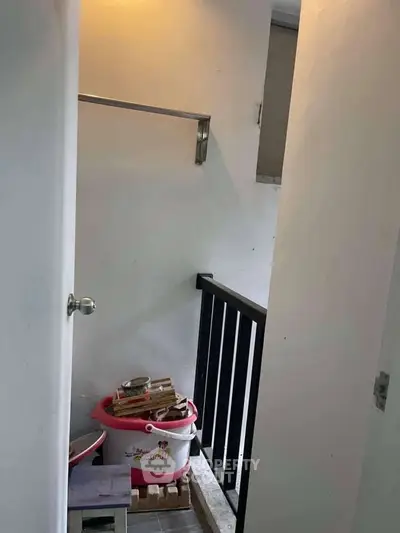 Compact storage area with railing and cleaning supplies, ideal for small spaces.