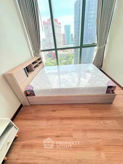 Modern bedroom with large window offering stunning city views and elegant wooden flooring.