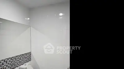 Modern bathroom with sleek white tiles and mosaic accent wall.
