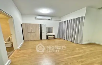 Spacious living room with polished wooden floors, large windows draped with elegant curtains, and a cozy fireplace, perfect for family gatherings.