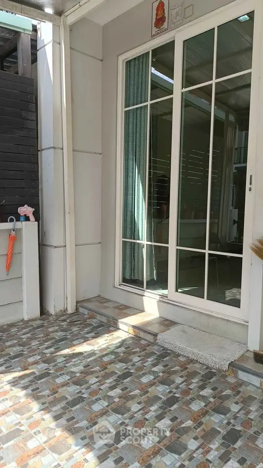 Charming patio entrance with sliding glass doors and mosaic tile flooring.