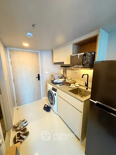 Modern compact kitchen with washing machine and sleek appliances in a stylish apartment.