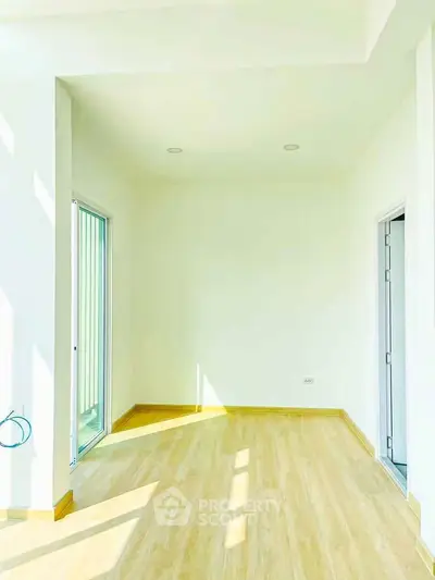 Bright and airy room with wooden flooring and large windows, perfect for a cozy living space.