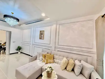 Elegant living room with plush sectional sofa and chandelier, perfect for modern comfort and style.