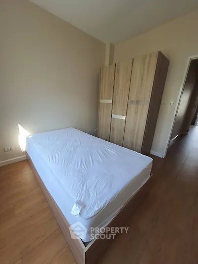 Spacious bedroom with wooden flooring and modern wardrobe, perfect for comfortable living.