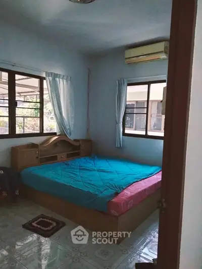 Cozy bedroom with large windows and air conditioning, featuring a comfortable bed and natural light.