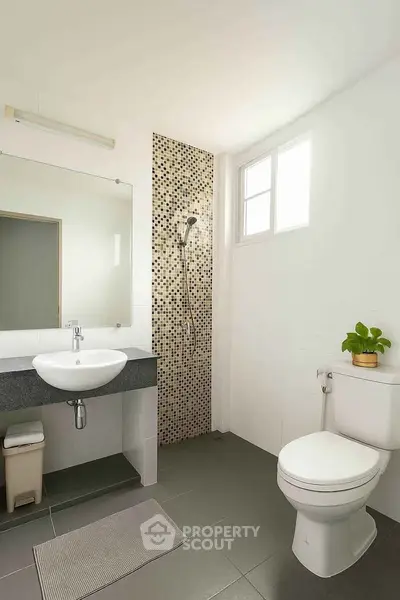Modern bathroom with sleek design, featuring a shower, toilet, and stylish sink area.