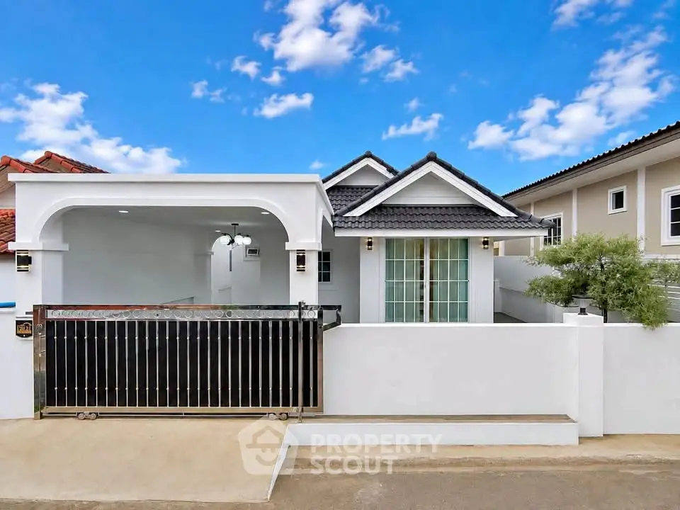 Charming single-story home with modern facade and gated driveway under a bright blue sky.