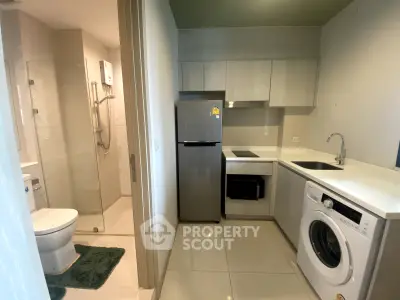 Modern compact kitchen with integrated appliances and adjacent bathroom in a stylish apartment.