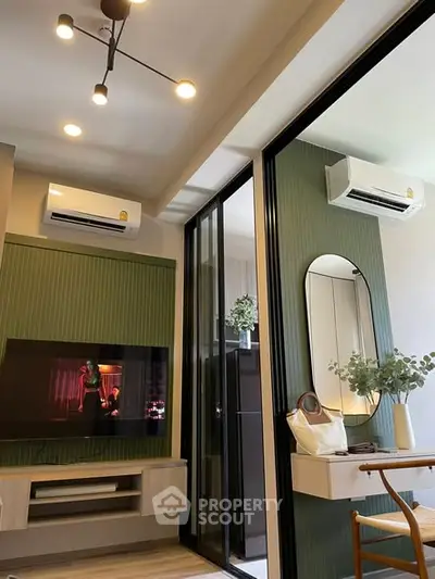Modern living room with stylish decor, wall-mounted TV, and air conditioning units.