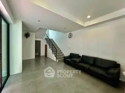 Spacious modern living room with sleek staircase and black leather sofas