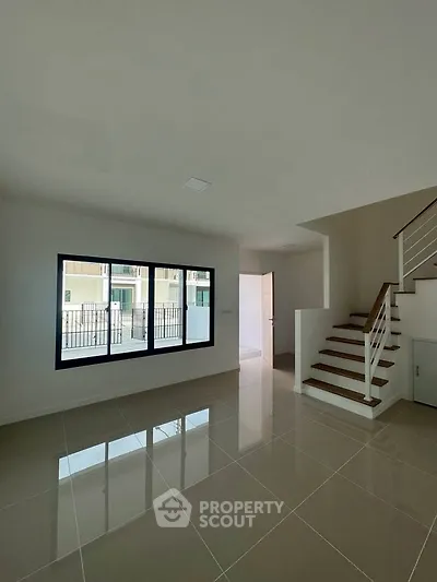 Spacious modern living room with large windows and sleek staircase