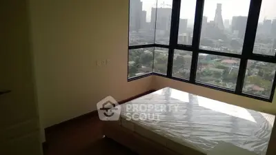 Spacious bedroom with large windows offering stunning city views in a modern apartment.