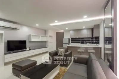 Modern open-layout living room and kitchen with sleek furniture and ambient lighting.